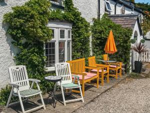 a group of chairs and a table and an umbrella at Bryn Euryn Cottage - 28135 in Llandrillo-yn-Rhôs