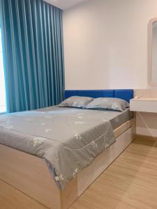 - un lit dans une chambre dotée d'un rideau bleu dans l'établissement Lahomestay Chỗ Nghỉ 2PN Tiện Nghi, Khách Hàng Yêu Thích, à Tân Vạn