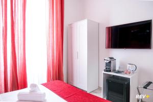 ローマにあるヴィアレ ジュリオ チェザーレ ゲストハウスの白いキャビネットと赤いカーテンが備わる部屋