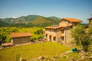 a stone house on a hill with mountains in the background at Villa La Voce Del Vento in Pastena