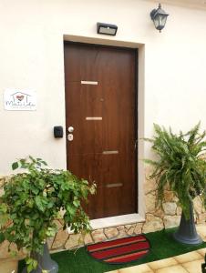 une porte marron d'une maison avec deux plantes dans l'établissement Matilde casa vacanze, à Santa Luria