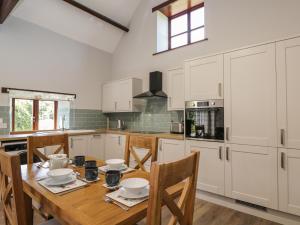 a kitchen with white cabinets and a wooden table with chairs at Swallow Barns in Bristol