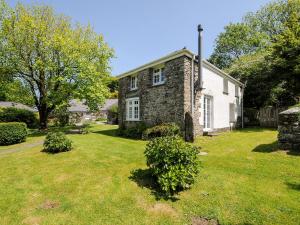 una antigua casa de piedra con un patio de césped en Byre en Camelford