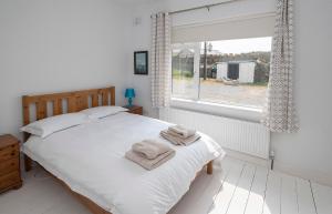 Un dormitorio con una cama y una ventana con toallas. en Clonea Beach Houses en Dungarvan