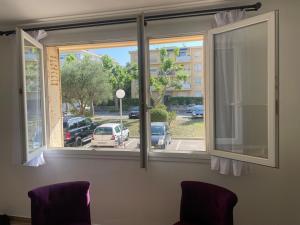 una ventana con 2 sillas que da a un aparcamiento en La Serane Appartement T3, en Marsella