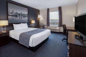 a hotel room with a bed and a flat screen tv at Super 8 by Wyndham Lachenaie/Terrebonne in Terrebonne