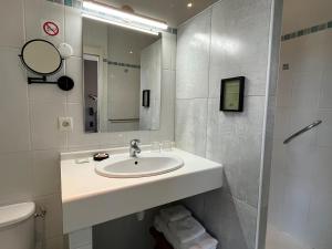 a white bathroom with a sink and a mirror at Hôtel Le Patio - Deauville in Deauville