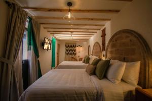 a bedroom with two beds with white sheets and green pillows at Casa Moseua Hotel Boutique de Autor in Querétaro