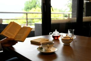 una persona leyendo un libro sobre una mesa con una taza de café en Hotel Marroad Hakone, en Hakone