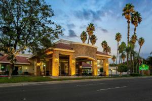 a building on the side of a street with palm trees at La Quinta by Wyndham Pomona in Pomona