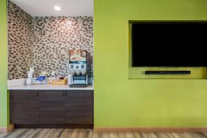 a green wall with a flat screen tv in a kitchen at La Quinta by Wyndham Pomona in Pomona
