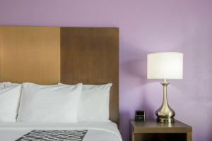 a bed with a lamp on a table next to it at La Quinta by Wyndham Pomona in Pomona