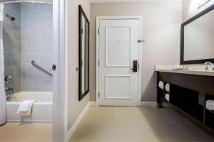 a bathroom with a white door and a sink and a tub at La Quinta by Wyndham Pomona in Pomona