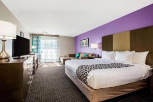 a hotel room with a large bed and a purple wall at La Quinta by Wyndham Pomona in Pomona