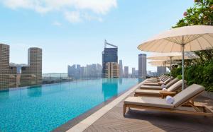 a pool with lounge chairs and umbrellas on a building at Andaz Singapore A Concept by Hyatt in Singapore
