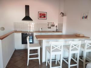 a kitchen with white chairs and a wooden counter top at Jerry & Oli's Apartments in Šibenik