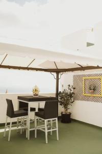 Apartamento de la Candelaria I في سانتا كروث دي تينيريفه: طاولة وكراسي تحت مظلة في غرفة