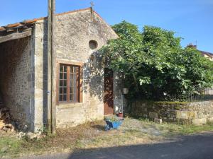 - un vieux bâtiment en pierre avec une porte et un arbre dans l'établissement Converted medieval chapel gite in Limousin country, à Rancon