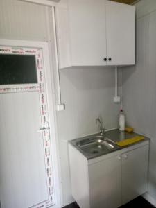 una pequeña cocina con fregadero y armarios blancos en Karavan Kır Evi, en Muğla