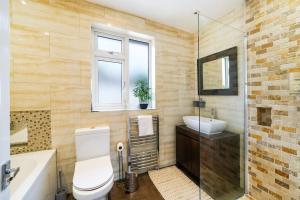 a bathroom with a toilet and a sink and a mirror at 3-bedroom, sleeps 5 with discounts on long bookings in Loughton