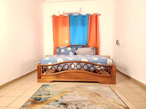 Schlafzimmer mit einem Bett mit blauen und orangefarbenen Vorhängen in der Unterkunft KADIDJA APARTMENTS & SUITES Akodessewa in Lomé