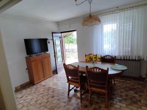 comedor con mesa, sillas y TV en Apartmani Doroteja, en Bibinje