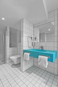 a bathroom with a blue sink and a toilet at Prize by Radisson, Hamburg St Pauli in Hamburg