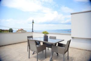 einen Tisch und Stühle auf einem Balkon mit Meerblick in der Unterkunft Panorama Hotel in Muggia