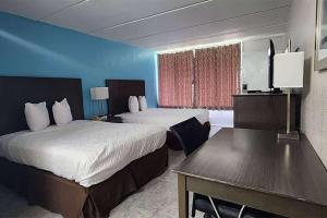 a hotel room with two beds and a table at Travelodge by Wyndham Kingsland GA in Kingsland