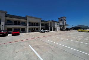 un grand bâtiment avec des voitures garées dans un parking dans l'établissement Baymont by Wyndham Freeport Texas, à Freeport