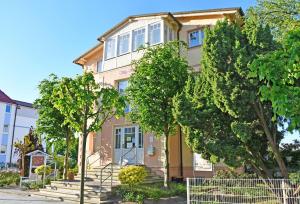 uma casa amarela com árvores em frente em Villa Vitalis _ Appartements und W em Ostseebad Sellin