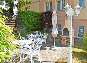 a group of white chairs and an umbrella on a patio at Villa Vitalis _ Appartements und W in Ostseebad Sellin