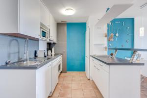 a kitchen with white cabinets and a blue wall at Paraiso II EQ FREE WIFI in Playa Paraiso
