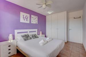 a bedroom with a white bed and a purple wall at Paraiso II EQ FREE WIFI in Playa Paraiso