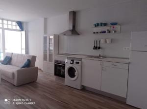 a white kitchen with a washing machine and a couch at Raquel Apartament in Alicante +1 photo