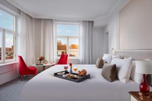 a hotel room with a white bed with a tray of food on it at Tivoli Doelen Amsterdam Hotel in Amsterdam