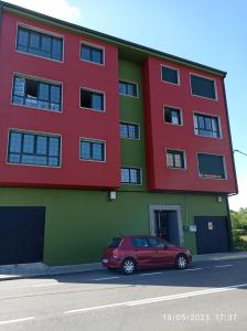 un edificio rojo y verde con un coche aparcado delante en AR Villa Rica Apartment en Santa Comba