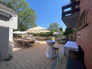 eine Terrasse mit Tischen, Stühlen und Sonnenschirmen in der Unterkunft Hotel / Gaststätte Jonen‘s Eck in Niederzier