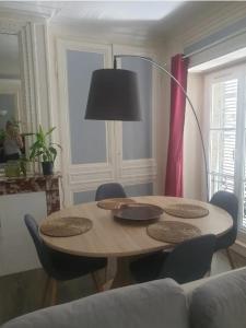 einen Tisch mit Stühlen und eine Lampe im Wohnzimmer in der Unterkunft Appartement idéal en centre ville in Pont-Audemer