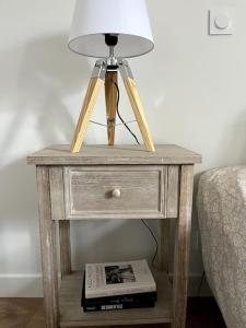 a bedside table with a lamp and a book at Cozy flat, quiet retreat w/ queen bed near forest in Barbizon