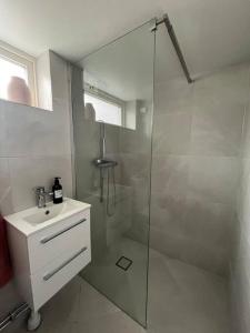 a white bathroom with a shower and a sink at Villa nära till natur och stan in Gothenburg