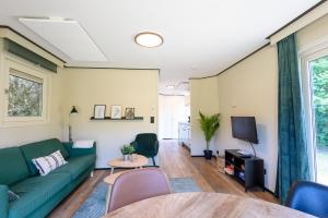 a living room with a green couch and a tv at Chalet met eigen tuin aan de Veluwse bosrand in Putten