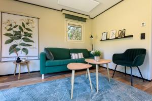 a living room with a green couch and two chairs at Chalet met eigen tuin aan de Veluwse bosrand in Putten