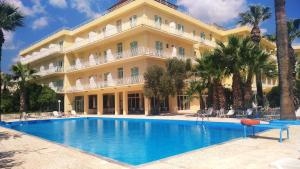 a hotel with a swimming pool in front of a building at Nireus Hotel in Nea Makri