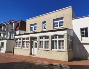 un gran edificio de ladrillo con ventanas blancas en una calle en Kleines Logierhaus 03, en Norderney