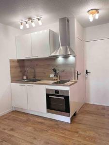 cocina con armarios blancos, fregadero y fogones en Appartement cosy, en Métabief