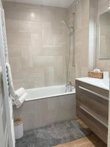 Baño blanco con bañera y lavamanos en Appartement cosy, en Métabief