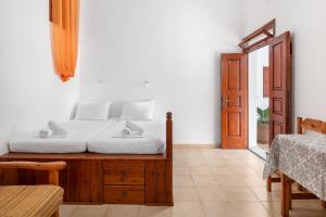 a bedroom with a bed with white sheets and a door at Apostolos Rooms in Lindos