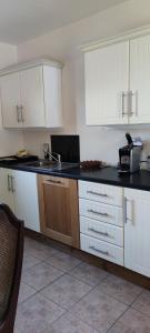 cocina con armarios blancos y encimera negra en The Garden Gates Guest Accommodation, en Castlebar