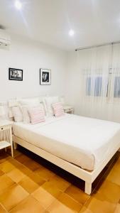 Cama blanca grande en habitación blanca con almohadas en Casa Nena Es Calo, en Es Caló